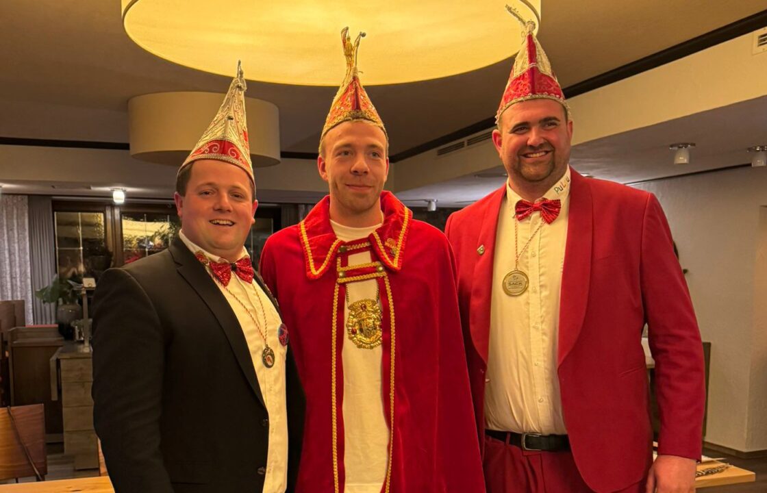 Prinz KeNo der Kickende im Ornat, Session 2025/2026, daneben zwei Mitglieder des Vorstands